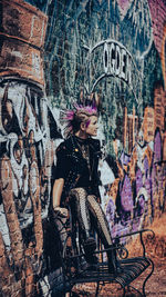 Woman sitting on graffiti wall