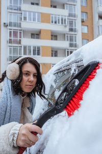 Portrait of young woman using mobile phone in city