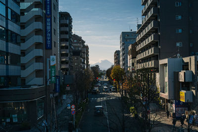 Cars on street amidst buildings in city against sky