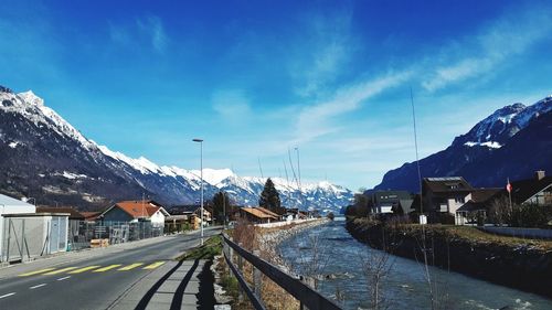 Road amidst buildings against sky during winter
