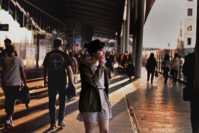 Young woman smoking while standing on street in city