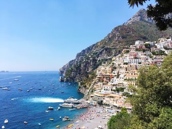 Aerial view of townscape by sea against clear blue sky