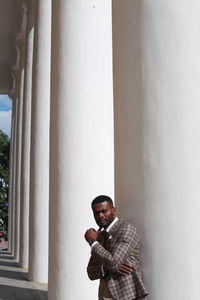 Portrait of young man standing against column