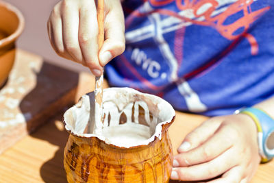 Midsection of man with paintbrush in container on table