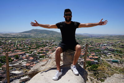 Full length of man with arms outstretched against cityscape