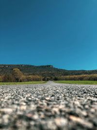 Surface level of road against clear blue sky