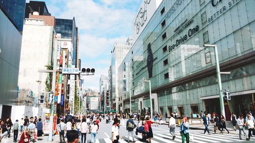 People walking on road against buildings in city