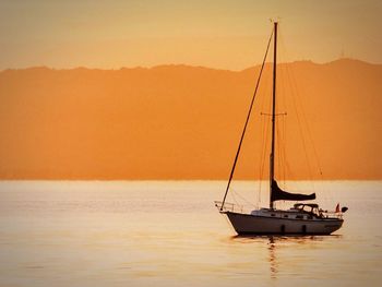 Boats sailing in sea at sunset