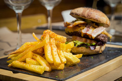 Close-up of french fries and burger served on table