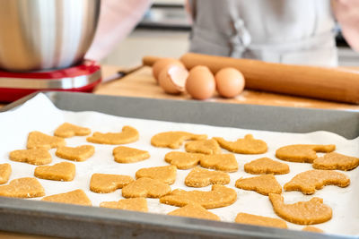 Woman baking cookies. cookies in shape of heart on oven paper. homemade pastries or cake.