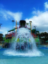 Water splashing in swimming pool against sky