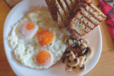 Close-up of egg omelet with mushrooms and breads in plate on table