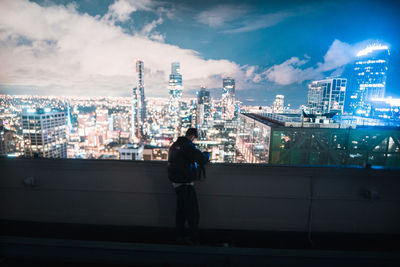 Rear view of man walking on street against sky at night