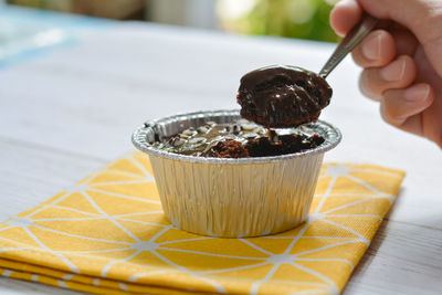 Eatting dark chocolate cake with chocolate chip topping in foil cup.