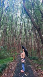 Rear view of woman standing in forest