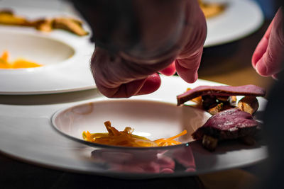 Cropped hands of person having food in plate