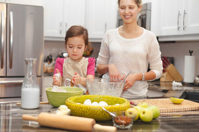 Cute girl with mother preparing food in kitchen