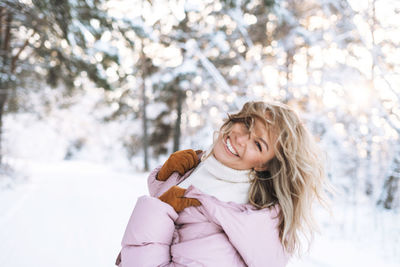 Portrait of young woman standing against trees during winter