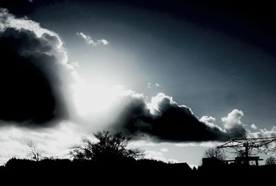 Low angle view of silhouette trees against cloudy sky