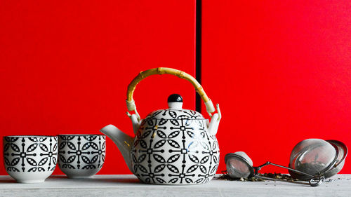 Close-up of crockery on table next to red wall