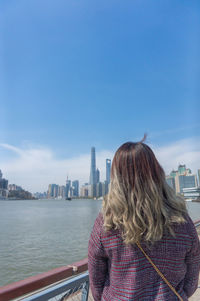 Rear view of woman standing by buildings against sky