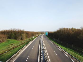 High angle view of highway by trees against clear sky