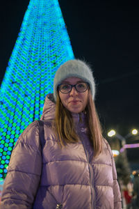 Portrait of young woman standing against sky at night