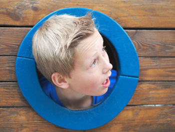 Close-up of boy peeking out a window