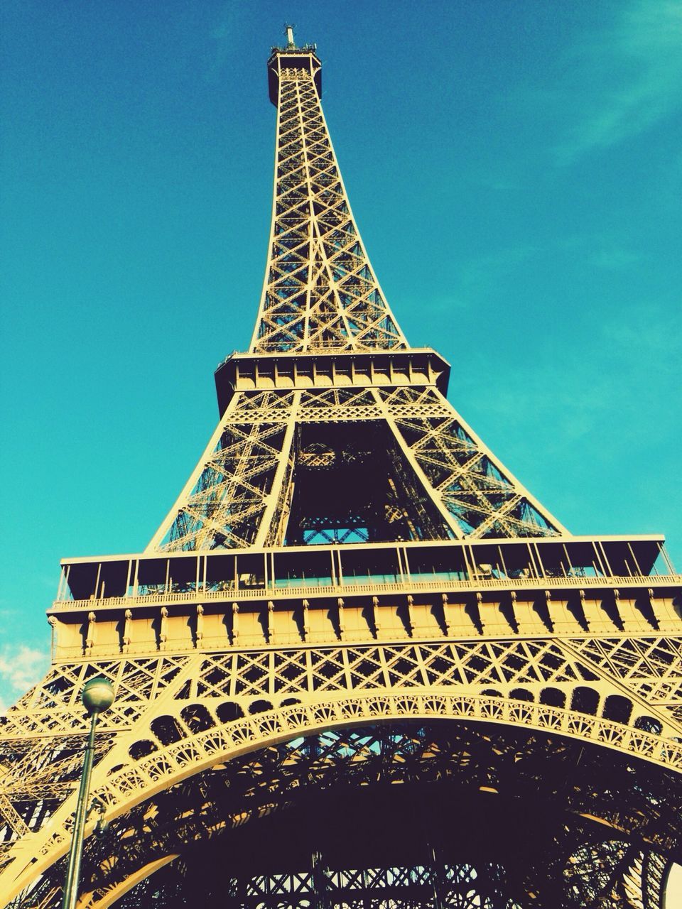 low angle view, famous place, eiffel tower, international landmark, architecture, travel destinations, built structure, tourism, tower, travel, capital cities, culture, tall - high, history, blue, clear sky, architectural feature, metal, monument, sky