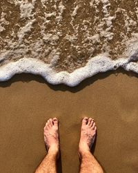 Low section of man standing on shore at beach