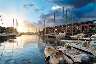 Boats moored in harbor at sunset