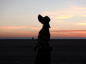 Silhouette man on beach against sky during sunset