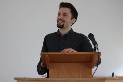 Smiling young man looking away against white background