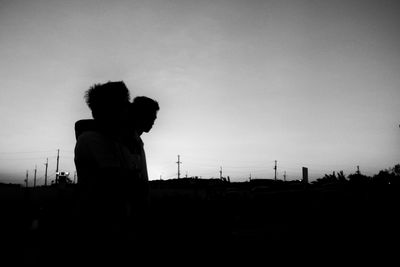 Silhouette man by fence against sky
