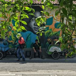 People on street amidst plants in city