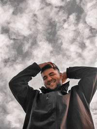 Portrait of young man looking at camera against sky