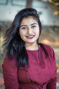 Portrait of young woman smiling while standing outdoors