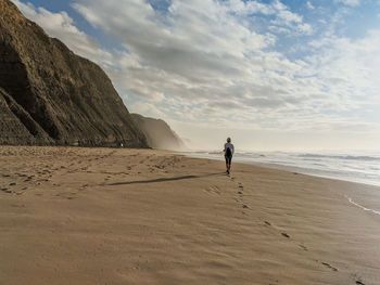 Full length of woman walking on beach against sky