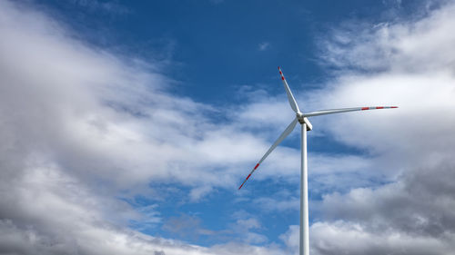 Single wind turbine against a heavily cloudy blue sky. renewable electricity production.