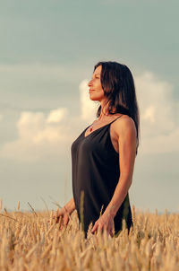 Beautiful woman with black hair on a wheat field. dreamy look. blue sky in background.
