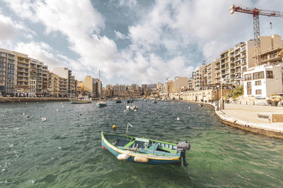 Boats in river against cloudy sky