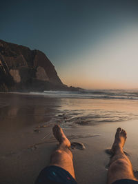 Low section of man on beach against clear sky