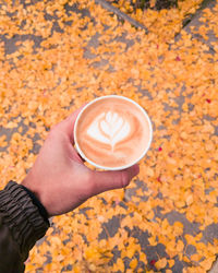 Hand holding coffee cup during autumn