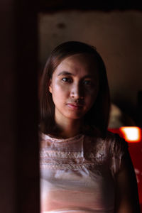 Portrait of woman standing against black background