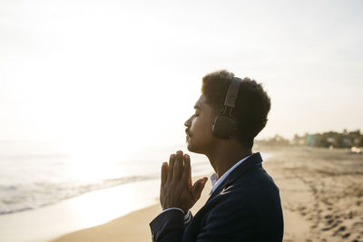 Portrait of young man on beach against sky