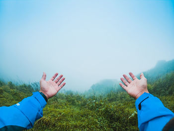 Cropped hands against sky during foggy weather