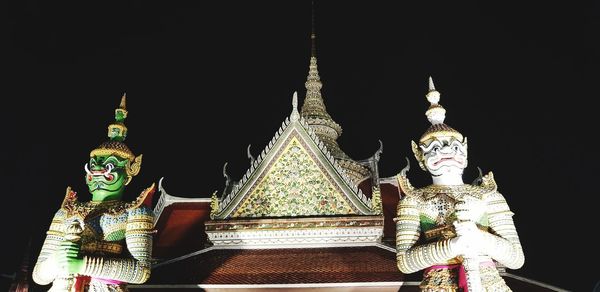 Statue of temple against building at night