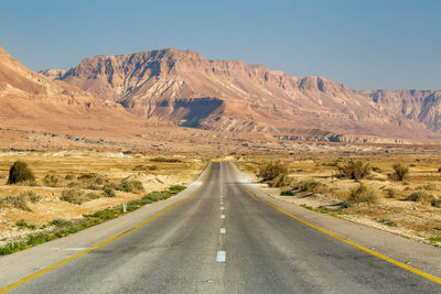 Road leading towards mountains against sky