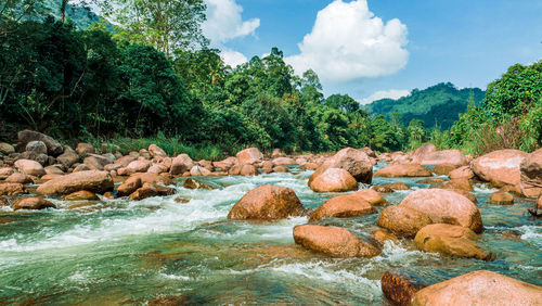 Rocks by river against sky