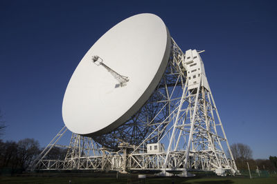 Low angle view of communications tower against clear blue sky